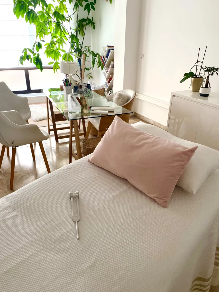 Espace de soin en bioénergie avec la table, plantes vertes et diapason thérapeutique pour une séance de relaxation profonde.